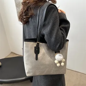 Minimalist large grey suede tote bag with black straps and plush pendant for work