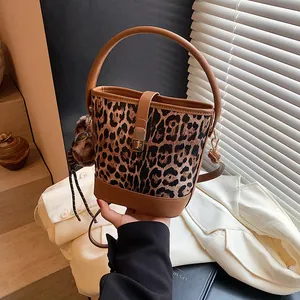 Detail of leopard print bucket bag with leather handle and plush charm accessory