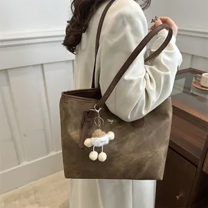 Large vintage brown tote bag with matte texture and plush charm accessory