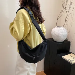 Detail view of black crescent canvas bag with adjustable wide strap on a model