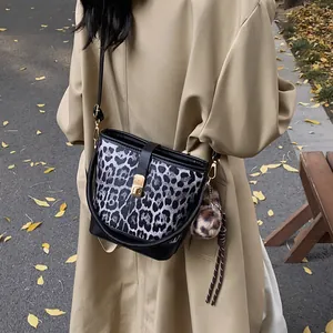 Stilvolle Bucket-Tasche mit Leopardenmuster und Goldschließe am Model im Herbst