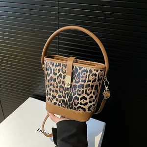 Schicke Beuteltasche mit Leopardenmuster, braunem Griff und goldenen Details auf Sockel
