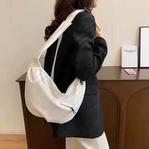 Detailed view of white faux leather crescent bag with smooth texture and wide strap