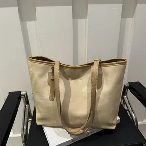 Macro detail of beige suede tote bag with brown straps on a minimal chair