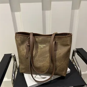 Detail of vintage brown tote bag with logo on a modern black chair with a book