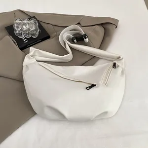 Detail showing beige moon-shaped crossbody bag with black zipper and adjustable strap