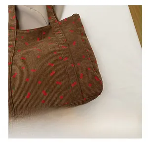 Détail du sac cabas en velours côtelé marron montrant la texture et l'imprimé cerise
