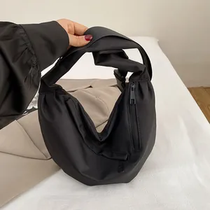 Detail of a black crescent nylon crossbody bag with side zipper pocket and wide strap