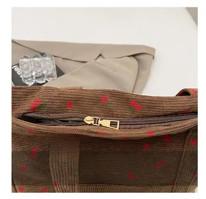 Détail de la fermeture éclair dorée fluide sur le sac cabas en velours à motif cerise