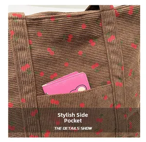 Détail du cabas en velours côtelé montrant la poche latérale avec motif cerise