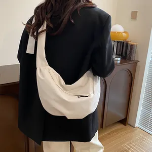 Minimalist cream white half-moon crossbody bag with wide strap and textured leather finish