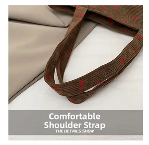 Détail de la bandoulière confortable sur un sac cabas en velours côtelé marron à cerises