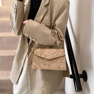 Detail of elegant beige crossbody bag featuring embossed koi fish and lotus patterns