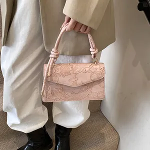 Detail of light pink handbag with embossed lotus and koi carp patterns and knotted handle