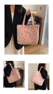 Détail d'un sac cabas en velours côtelé rose à motif cerises dans un décor douillet