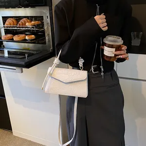 Detailed view of white embossed leather crossbody bag with floral pattern and knotted handle
