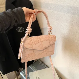 Close-up of pink embossed lady handbag with lotus and koi fish patterns and knotted handle