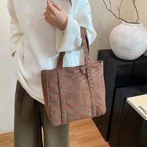 Vue détaillée du sac cabas en velours côtelé marron avec imprimé cerises sur un mannequin