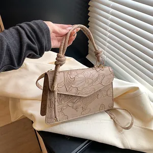 Detail of elegant beige crossbody bag with embossed koi and lotus flower motifs