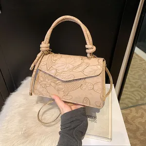 Detail of elegant beige handbag featuring embossed koi fish and lotus floral texture