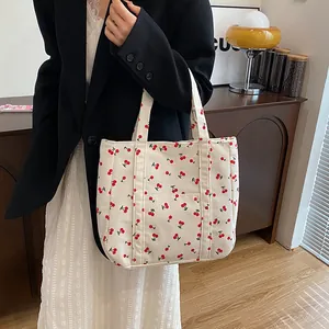 Détail d'un sac cabas en velours côtelé avec imprimé cerise et poche avant