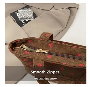 Detail of a smooth metal zipper on a premium brown corduroy tote bag with strawberry