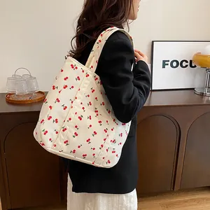 Détail d'un sac cabas en velours côtelé avec imprimé cerise porté par un mannequin chic