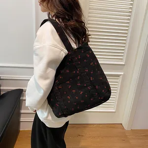 Détail du sac cabas en velours côtelé noir avec motifs cerises rouges et poche latérale
