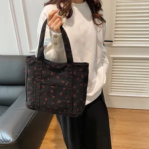 Détail du sac cabas en velours côtelé noir avec motifs cerises et poche avant