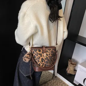 Detail of leopard print bucket bag with plush pompom charm and adjustable strap