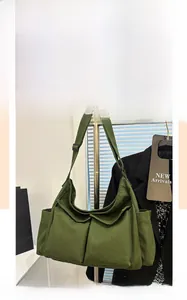 Dettaglio della borsa a tracolla in tela verde scuro con tasche multiple e stile retro workwear