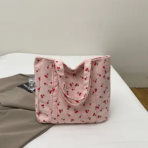 Détail du sac cabas en velours côtelé rose avec motif cerises et poignées solides