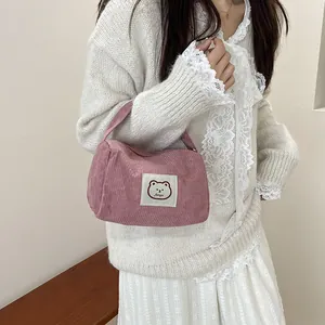 Pink corduroy handbag detail with fanyu bear label held by a model in lace knitwear
