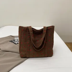 Détail du sac fourre-tout en velours côtelé marron avec motifs cerises et texture à côtes