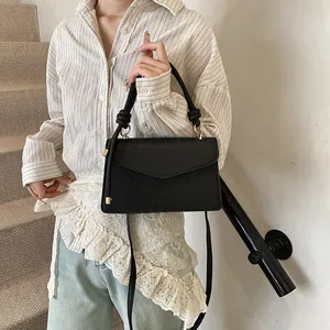 Detail of black embossed PU leather handbag with unique braided top handle and gold hardware