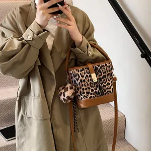 Close-up of leopard print bucket bag featuring brown leather trim and heart charm detail