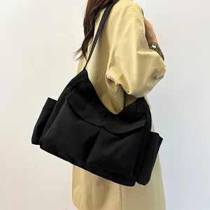 Dettaglio di una borsa a tracolla capiente in tela nera con tasche multifunzione
