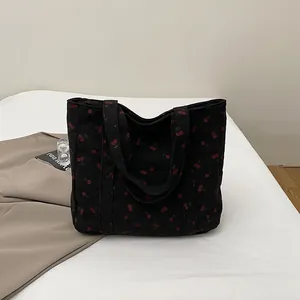Détail du sac fourre-tout en velours noir à motif cerises sur fond blanc minimaliste