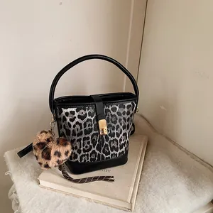 Detail of leopard print bucket bag featuring gold metal clasp and heart plush pendant