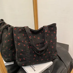 Détail du sac cabas en velours côtelé noir à imprimé cerise reflété dans un miroir chic