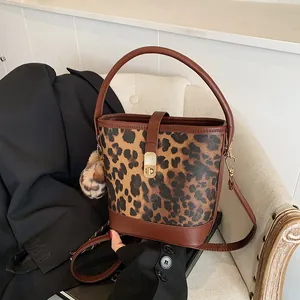 Detailed view of leopard print bucket bag with gold hardware and plush charm on chair