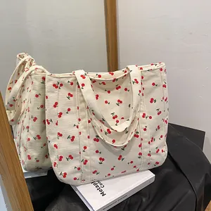 Détail du sac cabas en velours côtelé blanc avec motifs de cerises et anses robustes