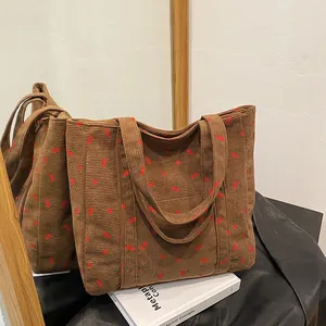 Détail du sac cabas en velours côtelé marron avec broderie cerise et texture côtelée douce