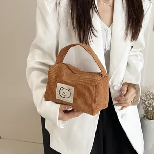 Close-up of brown corduroy handbag featuring a cute cartoon bear patch and soft texture