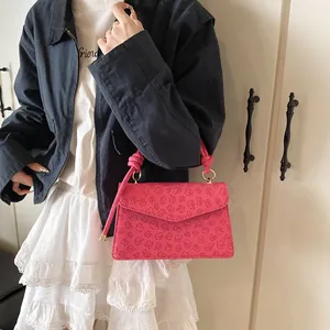 Detail of rose pink crossbody bag with clover embossing and gold circular hardware