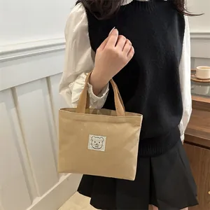 Détail du sac à main en toile avec écusson ours dessin animé et anses solides