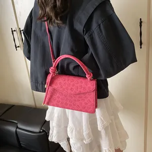 Deep pink small square bag with 3D floral embossing shown worn on the shoulder