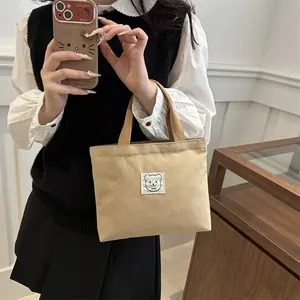 Gros plan du sac fourre-tout en toile minimaliste avec écusson d'ours et anses en tissu