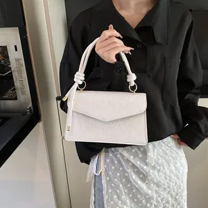 Detail of white leather handbag with embossed floral patterns and knotted handle detail