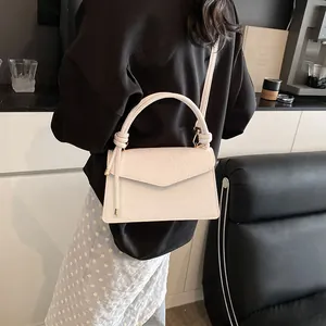 Close-up of embossed floral pattern and knotted handle on a white faux leather bag